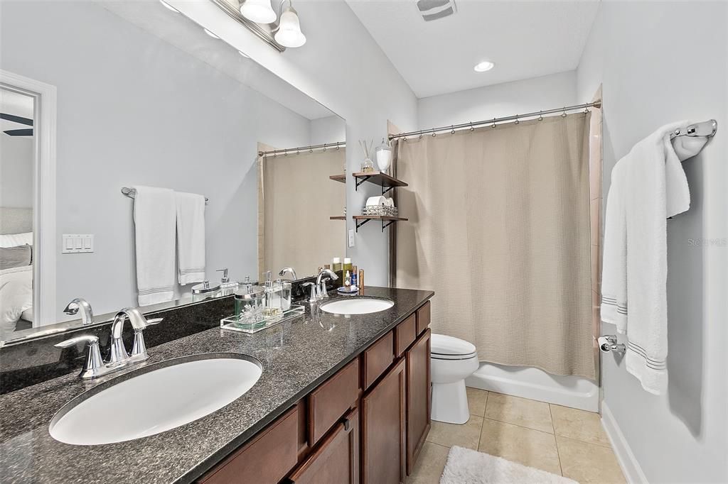En-suite bathroom for primary bedroom: double vanity with granite countertops, tile shower with tub