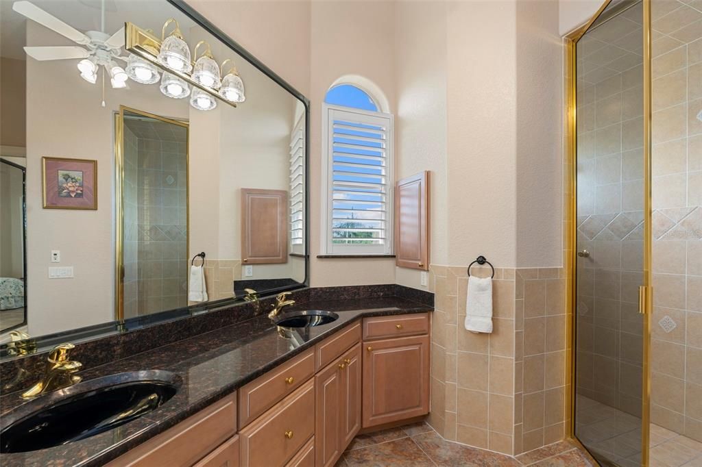 The in-law suite full bath features dual sinks, solid wood cabinetry, and steam shower