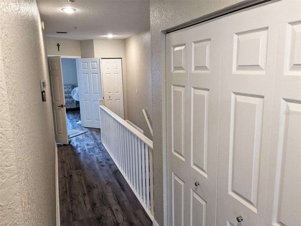 Upstairs hallway looking toward master suite.  Laundry closet behind doors on right. Side by side washer and dryer are included.