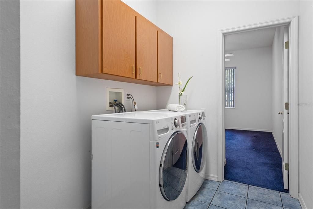 Interior laundry room with wall hung cabinetry and front load washer/dryer