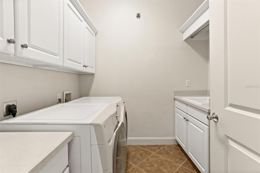 Laundry room with lots of storage and utility sink on the right with hanging rod.