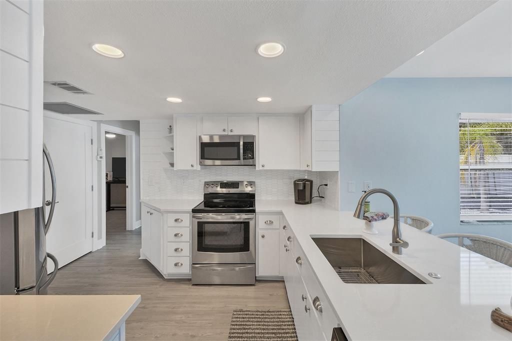 Refreshed kitchen with quartz countertops, marble backsplash and stainless steel appliances.
