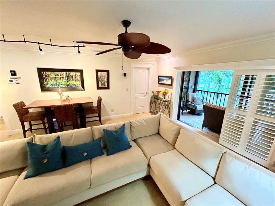 The living area extends to the lanai with sliders and plantation blinds.