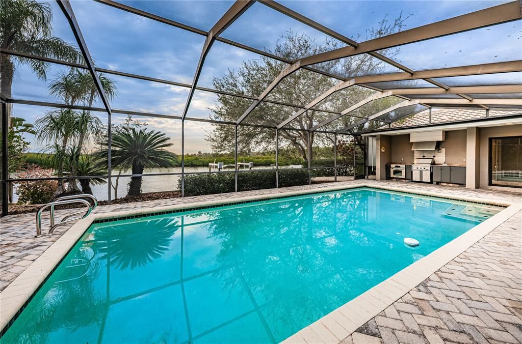 Heated, pebble-tec pool with outdoor kitchen area overlooks water and conservation.