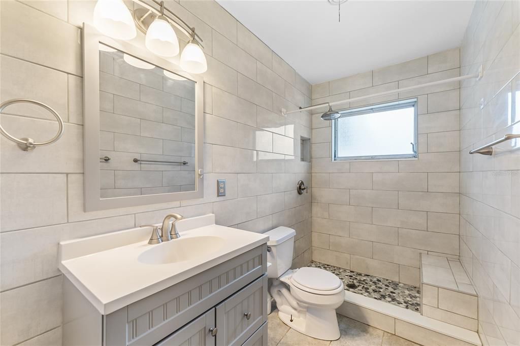 Beautifully updated bathroom featuring tile and abundant lighting