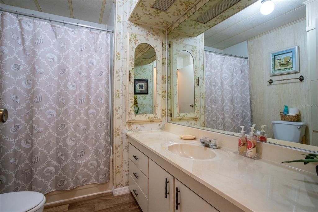 Large guest bathroom with built-in storage and laundry hamper