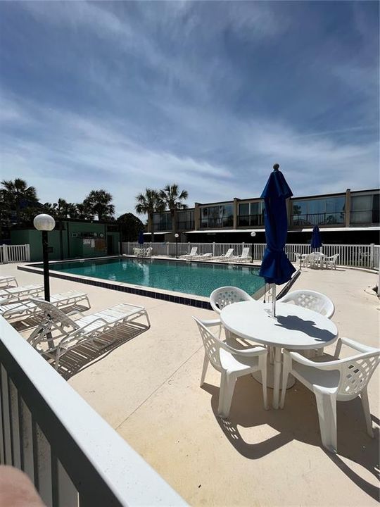 Fully fenced pool with chairs, tables and umbrellas