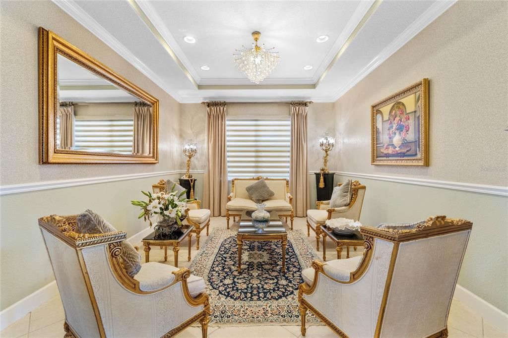 Formal living room complemented by tray ceiling, chair rail and crown molding.
