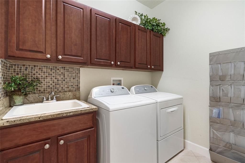 A convenient upstairs laundry with granite counter, sink and built-in storage adds practicality to daily life