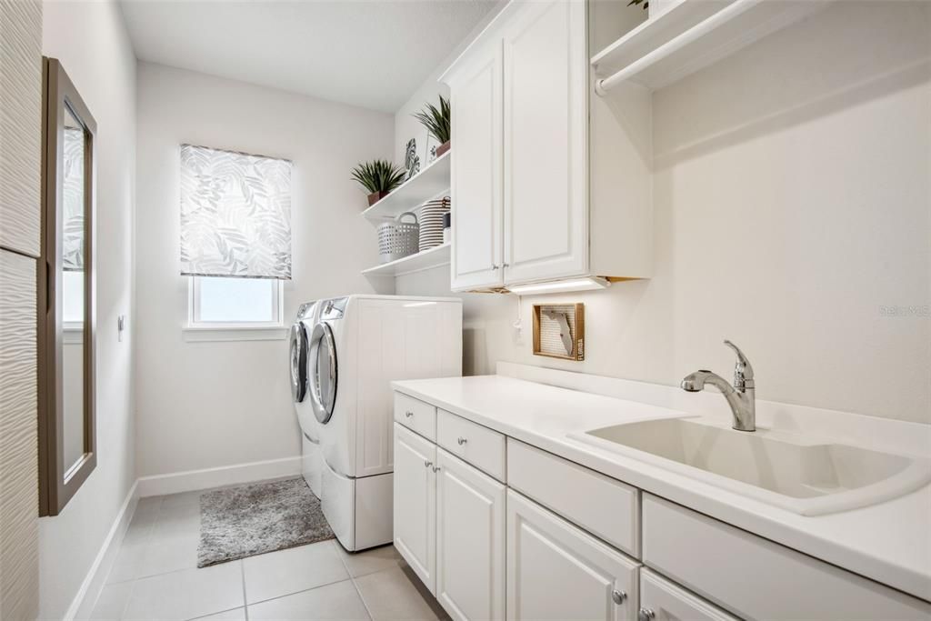 Laundry room has custom cabinetry, laundry sink, drying rod plus closet for storage and there is also a built in ironing board.