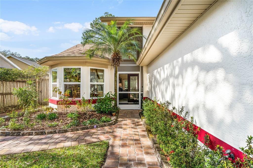 The front entrance offers a screened and covered front porch with welcoming Florida native landscaping.