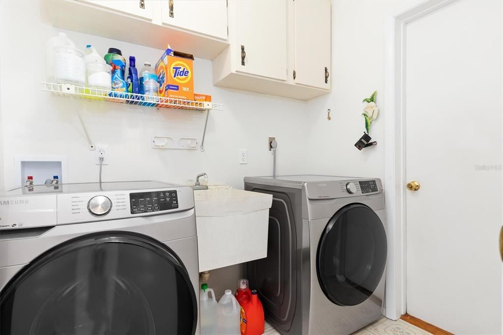 Spacious interior laundry with NEW SS washer and dryer. The utility sink and cabinets add to this rooms functionality. Door in background leads to garage.