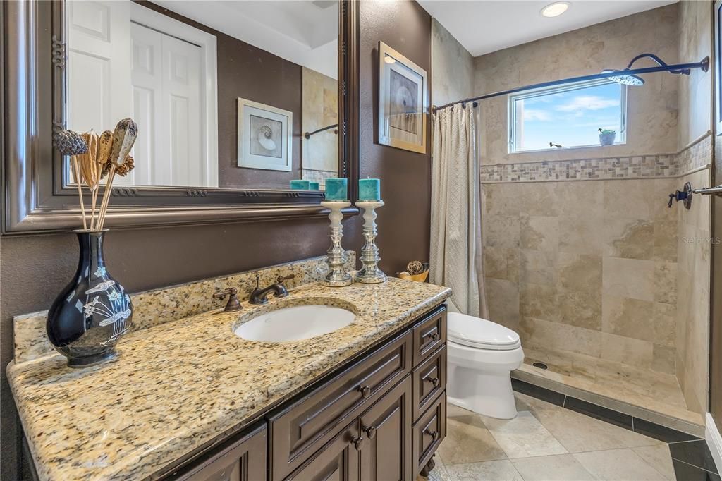 Guest bathroom with granite counters and tile floors.