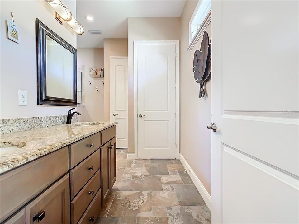 Double sinks in granite counters separate walk in shower and private door on toilet room