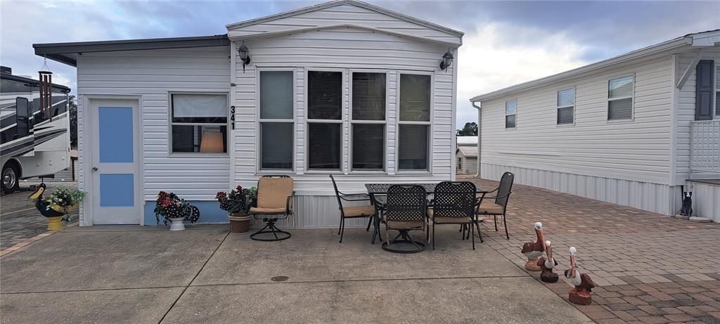 FRONT VIEW W/ NEW DOOR & PAVED DRIVEWAY. ON LEFT IS ANOTHER LOT WITH MOTOR HOME.