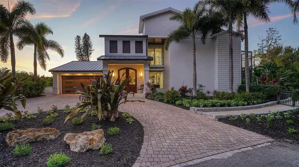 Front view of home with paver circle drive and beautiful landscaping. This home is Florida living at its best. with a Coastal Luxury design that allows outdoor living at its finest. Be sure to browse all the photos to get the best experience