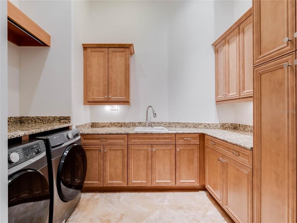Laundry room with sink and plenty of storage, complete with folding area.