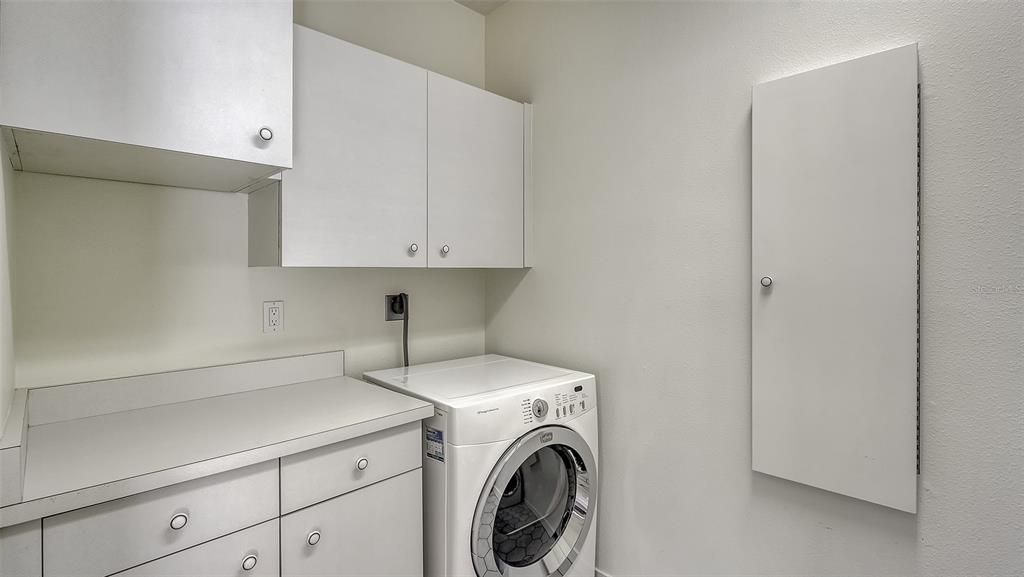 First floor laundry room offers a utility sink, storage and laundry chute from the primary bedroom closet.