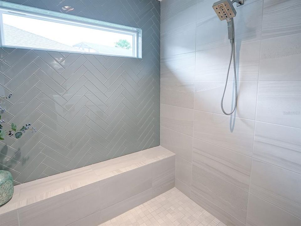 WINDOW PROVIDES NATURAL LIGHTING AND A BENCH THE LENGTH OF THE SHOWER.