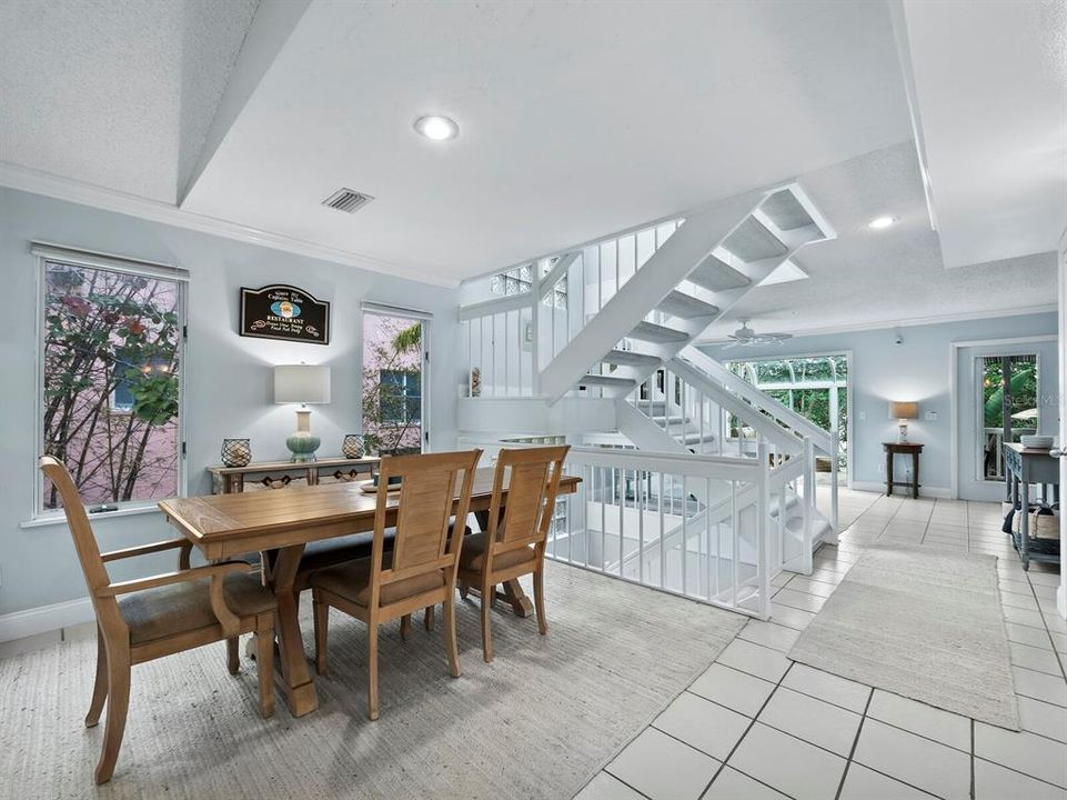 The dining room, adorned with expansive windows, enjoys a connection to the outdoors and a staircase leading to the elevated charm of the third floor.