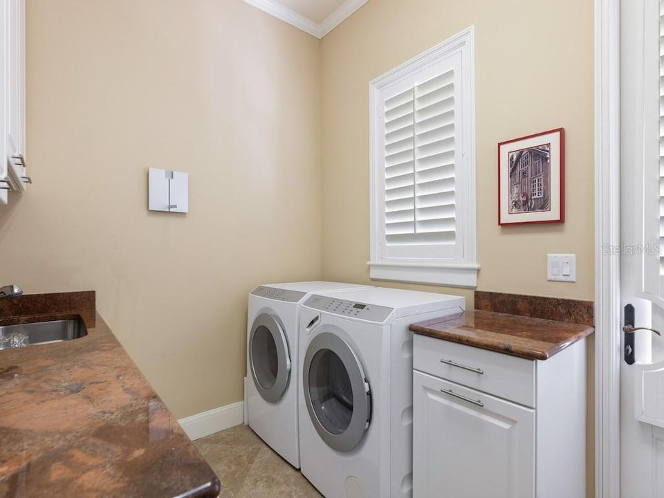 Laundry room off kitchen features custom cabinetry, wash sink, granite counters and secondary refrigerator