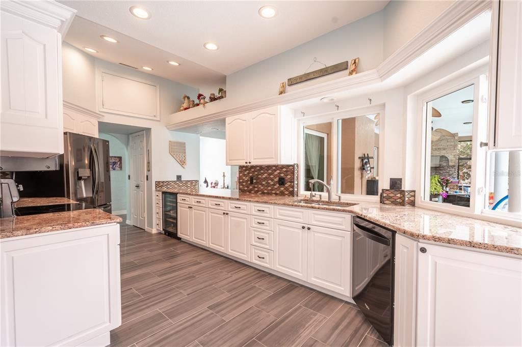 The kitchen features a ceramic tile wood plank floor, recessed lighting and a full suite of appliances including a wine fridge.