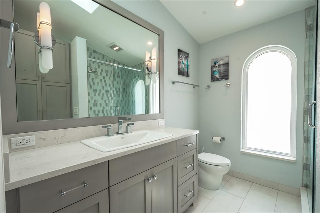 The 3rd bathroom features a mirrored vanity with light sconces and storage.