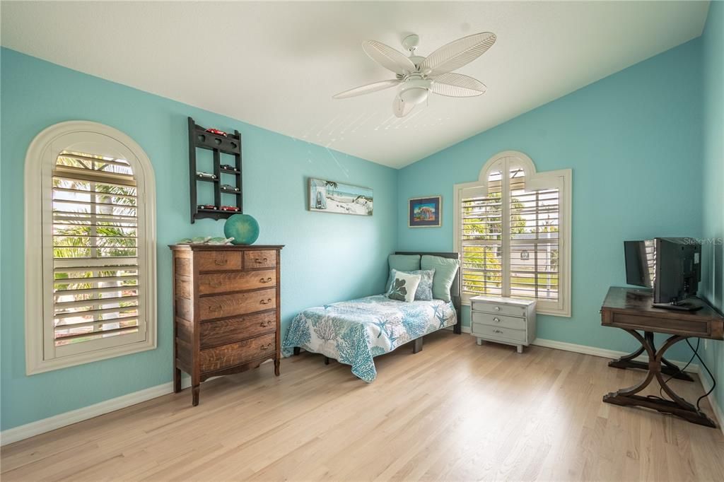 Bedroom 3 features high ceilings with ceiling fan, a built in closet, wood floor and plantation shutters.