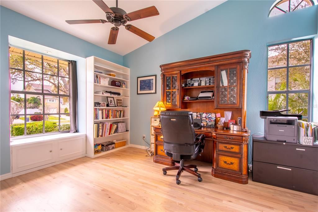 Bedroom 2 is currently used as an office . It features wood floors, high ceiling with ceiling fan, window seat, built in closet and cabinets, and a pocket door with access to the pool bath.