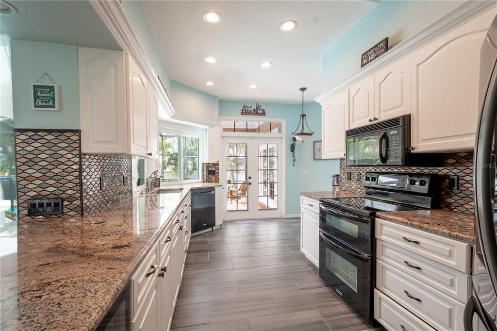 The kitchen has an abundance of granite counter space with a decorative glass backsplash.