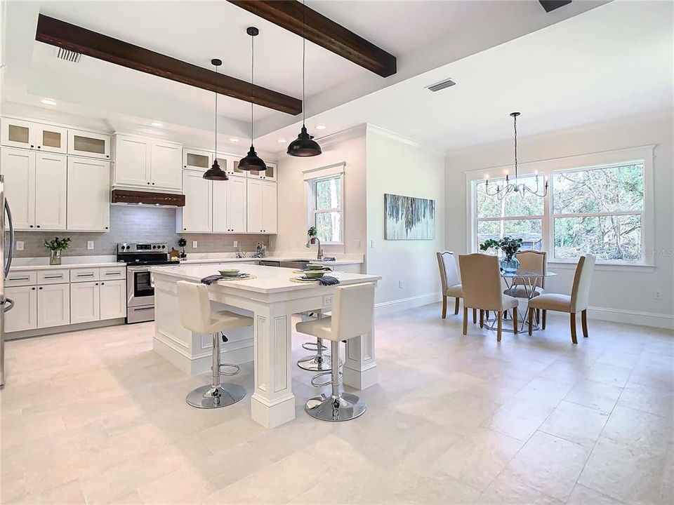 Amazing Chef's kitchen complete with island with seating and custom stained beams with great views of the backyard