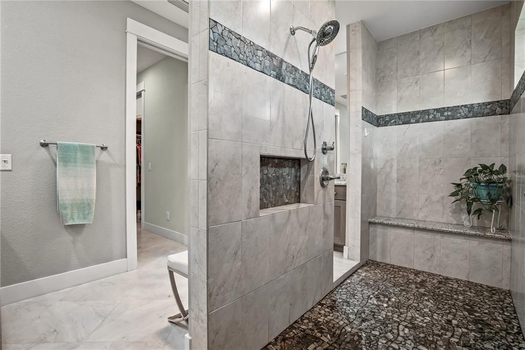 THE PRIMARY BATHROOM FEATURES A HUGE WALK-THRU SHOWER WITH BENCH