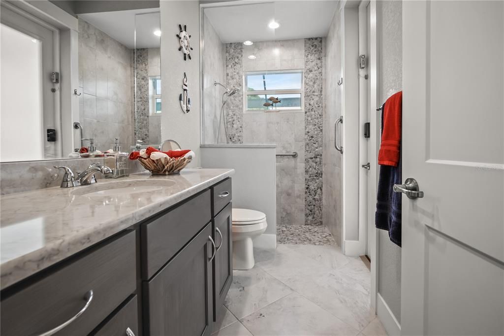 THE MAIN BATHROOM HAS A BEAUTIFUL WALK-SHOWER, LARGE VANITY AND EASY ACCESS TO THE POOL AREA
