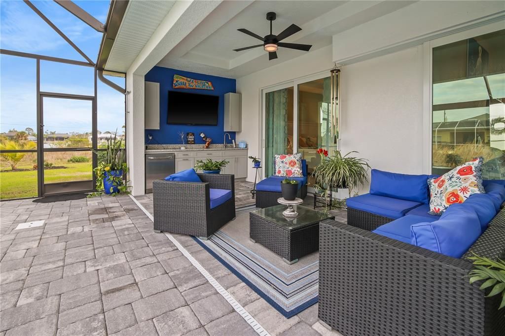 IMAGINE HAVING HAPPY HOUR IN THIS RELAXING SPOT, OVERLOOKING THE POOL. THE WICKER SET WITH BLUE CUSHIONS, TABLE AND RUG REMAINS