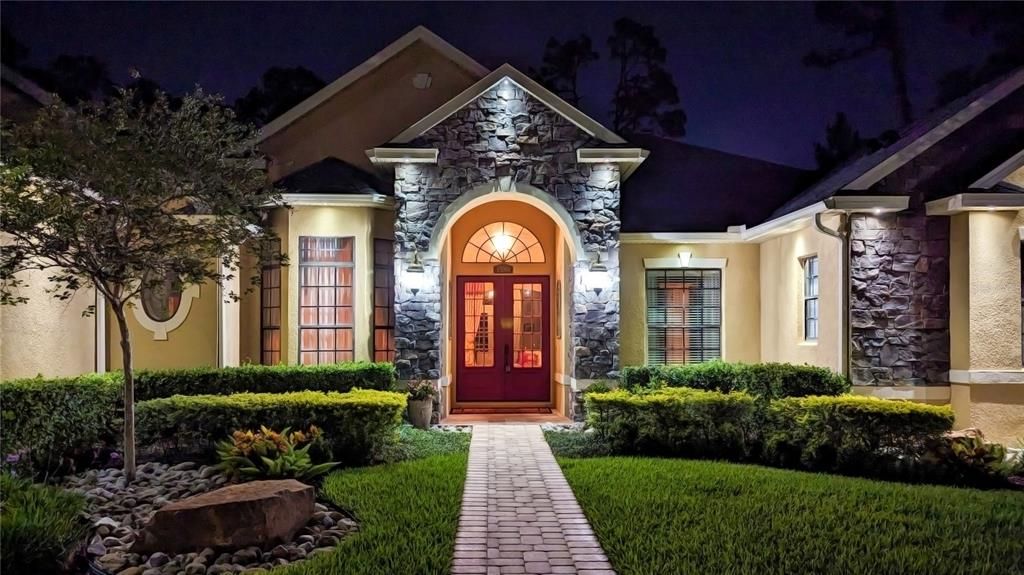 Come home to an elegant entrance with stone accents, a grand arched doorway, and beautiful landscaping.