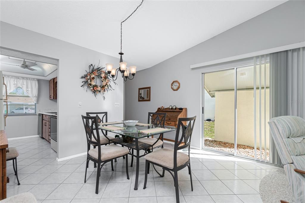 The dining area has diagonal tiled flooring, a sliding glass door to the exterior, and a updated light fixture.