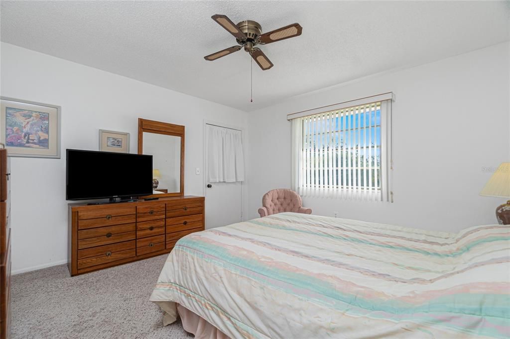 The master bedroom has carpeted flooring, a ceiling fan and direct access to the Florida room.