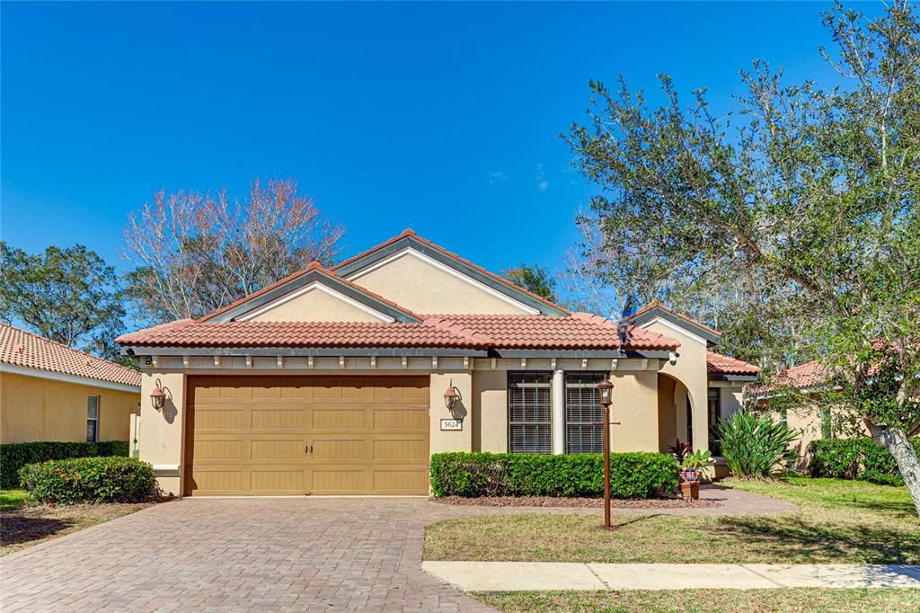 Beautiful well manicured home with tile roof, architectural wood sconces, pave driveway and walkway. Arched entryway into the covered porch area.