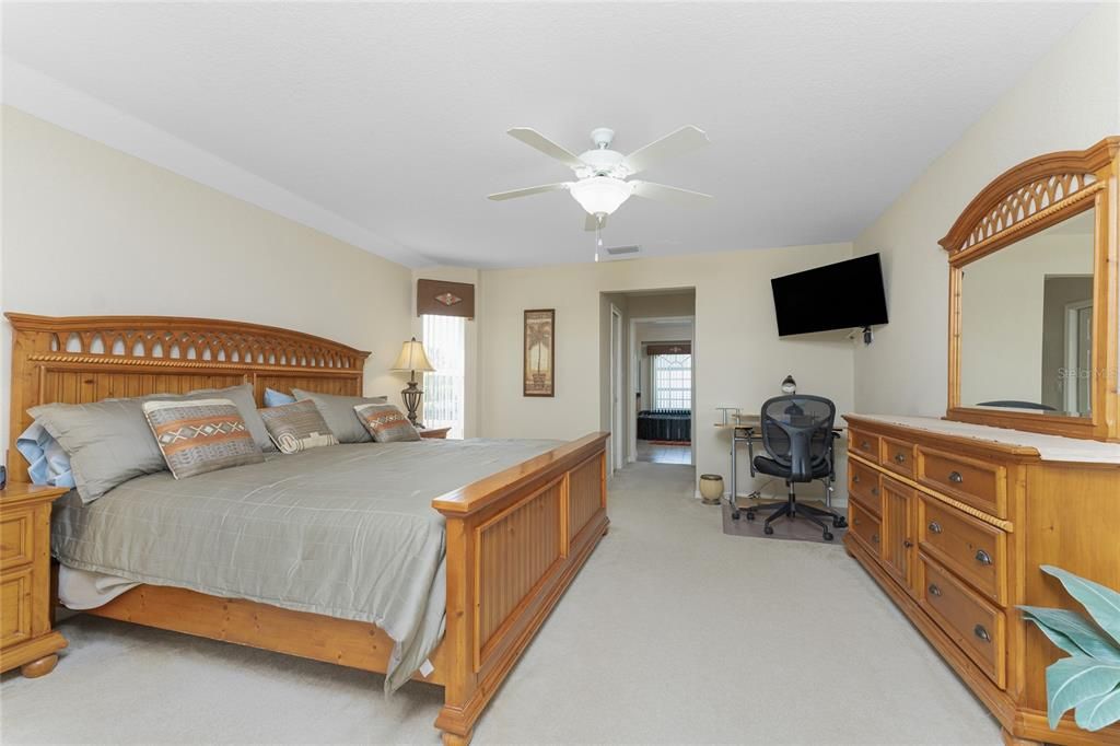 The master bedroom has carpeted flooring and a ceiling fan, with two walk in closets.