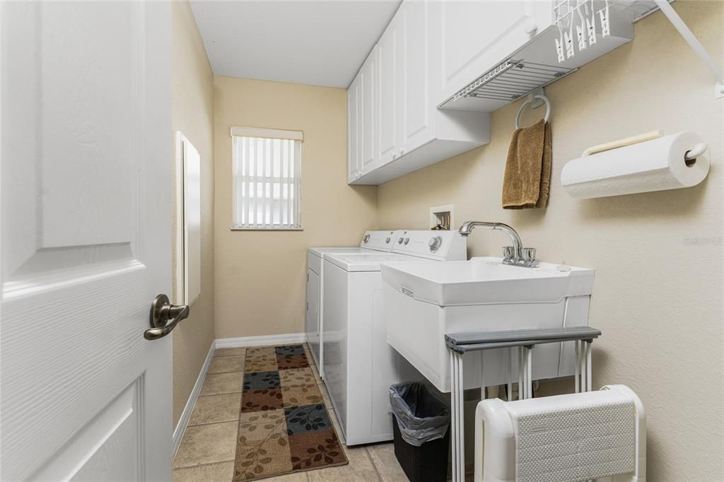 The inside utility room has built in upper cabinets, washer and dryer, and utility tub.