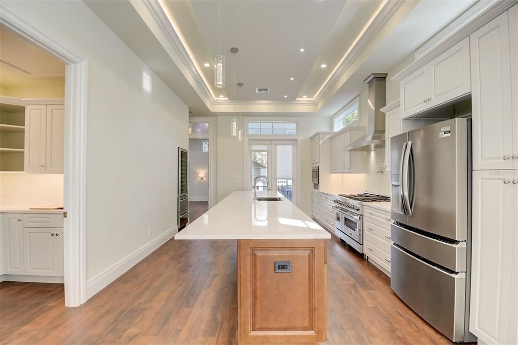 Spacious Open Kitchen with two tone cabinets, quartz countertops and top of the line appliances with view to left into Butler's Pantry/Laundry Room compete with sink!!!