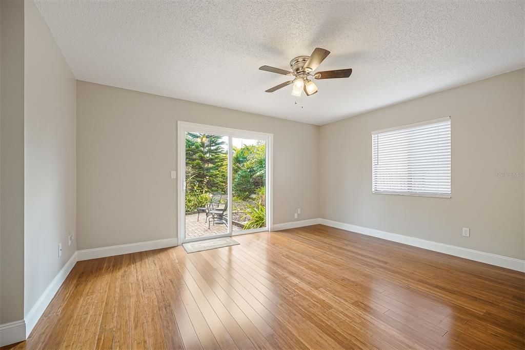 Master or Primary bedroom. Bamboo Flooring. New Sliding Doors,  Insulated. Looking into back yard on open patio. Ceiling fan window dressings.