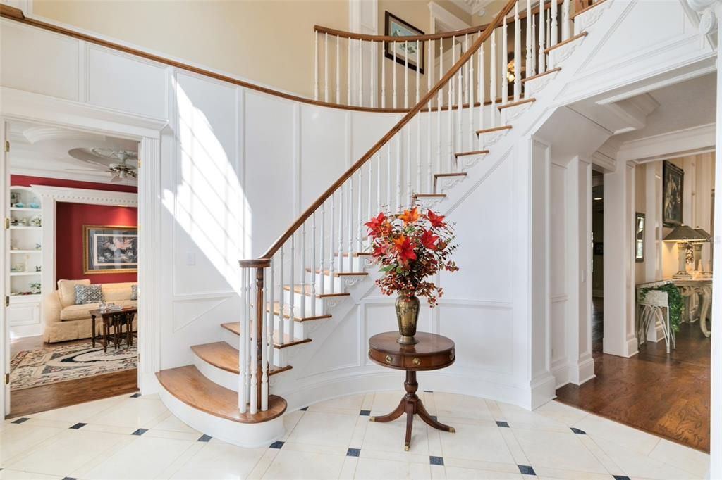 The grand entryway, marked by a majestic, curved staircase.