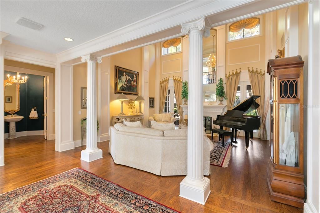 The formal dining room and living room are defined by stately columns and crown molding, enhancing the regal ambiance.