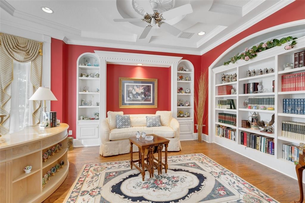 To the left, a welcoming library adorned with built-in bookcases offers a serene retreat for literature enthusiasts.