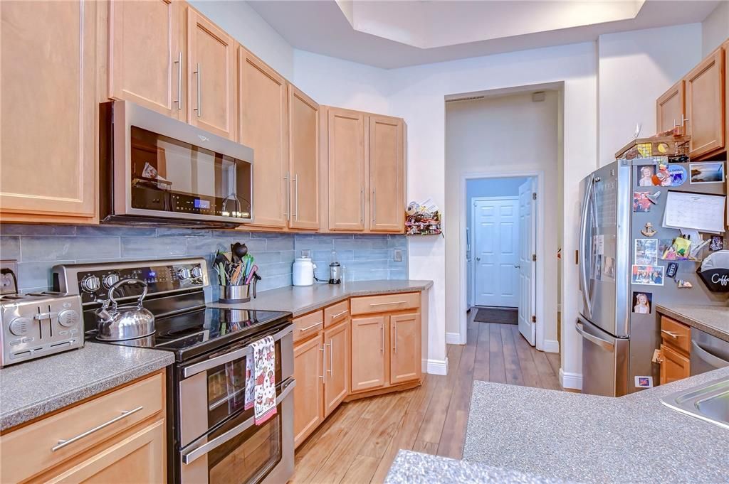 Beautiful kitchen boasts a tray ceiling, elegant wood cabinets, and beautiful tile backsplash!