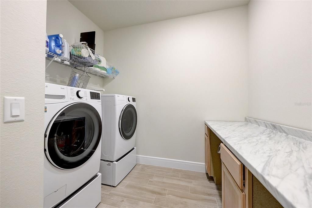 The laundry room has beautiful cabinets and a large work area.