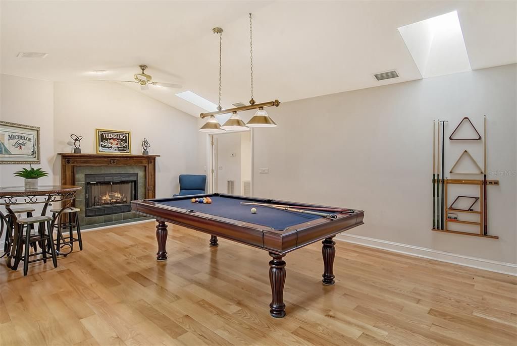 The game room with high ceilings, fireplace and wood floors.  This is connected to the primary bedroom and would work as an in-law suite.