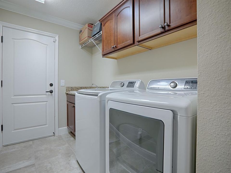 LAUNDRY ROOM OFF THE KITCHEN WITH BUILT-IN SINK, GRANITE COUNTERS, EXTRA CABINETS AND HANGING RACK, WASHER AND DRYER DO CONVEY WITH THE HOME. THIS DOOR LEADS TO THE GARAGE.