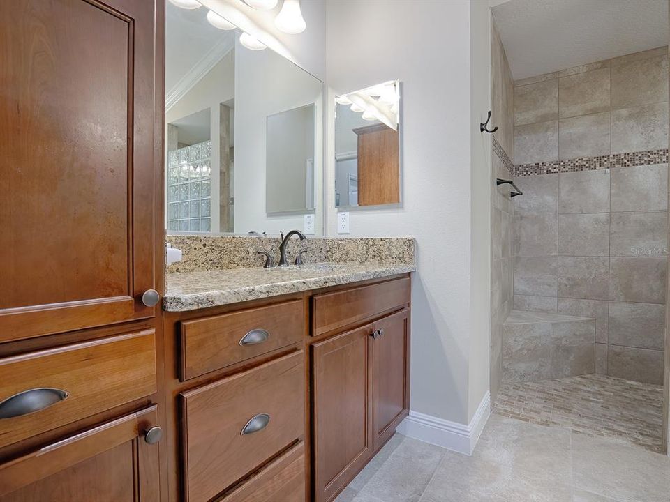 PRIMARY BATH WITH GRANITE COUNTERS, DUAL VANITIES, AND ROMAN SHOWER.